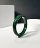 A grade Rich green jade bangle bracelet on a white surface with a dark background