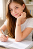 Young girl with a jade bead red string bracelet, smiling at the camera.