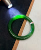 Green jade bracelet on a dark surface with a light source