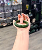Hand holding a green jade bracelet in a store setting under natural indoor light