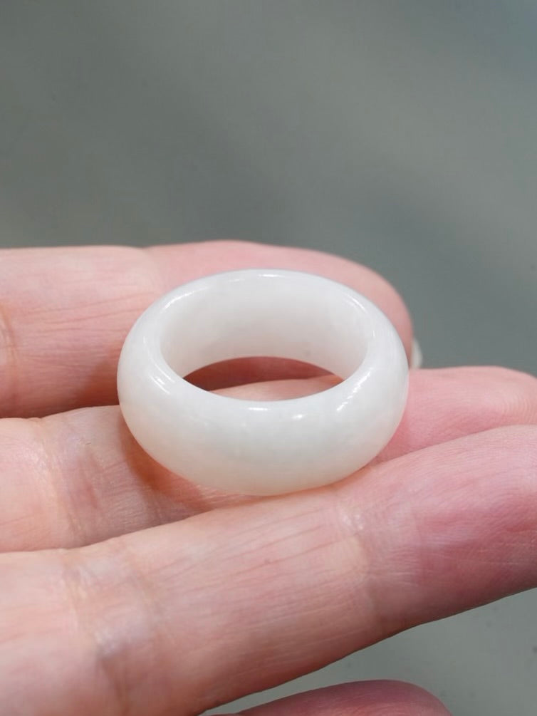 Natural Hetian white nephrite jade domed wide band ring resting on an open hand