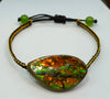 Ammolite bracelet with an orange and green iridescent gemstone, black and gold braided cord, and green bead ends.