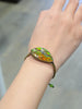 Close-up of an ammolite bracelet worn on the wrist, showing its green and orange gemstone and black and gold cord.