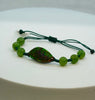 Ammolite bracelet with an iridescent green gemstone, six round green beads and an adjustable dark green cord.