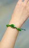 Ammolite bracelet worn on the wrist, showing a green and blue iridescent gemstone flanked by round green beads.