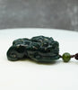 Hand-carved Canadian Polar Nephrite Jade Pixiu pendant resting on a surface, featuring deep spinach green color, intricate details, and a matching jade bead #2441.