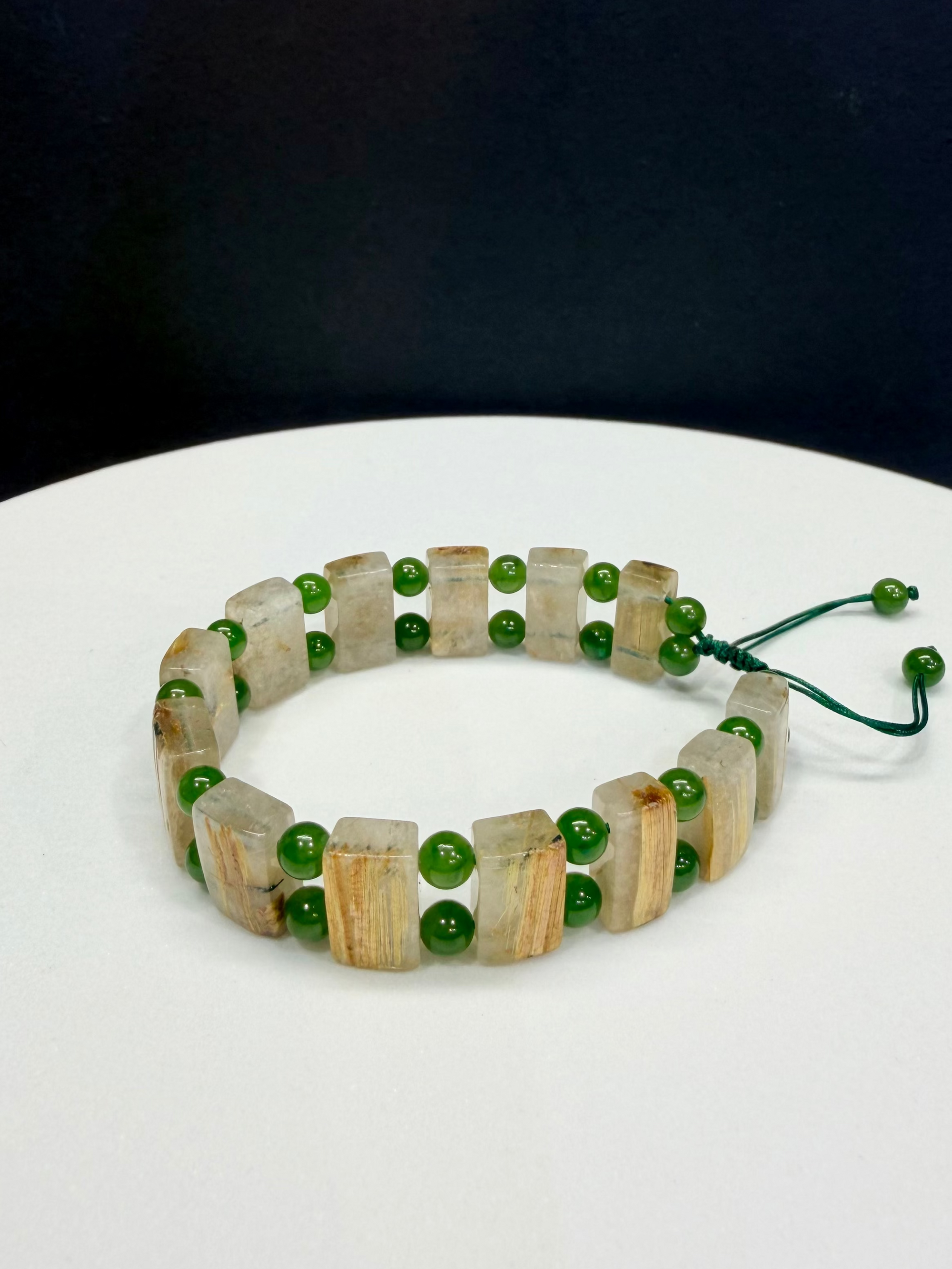 Double-strand handmade gemstone bracelet featuring square-cut gold rutilated quartz crystals and round green Polar jade beads on a white surface.