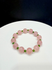 Hand-braided healing crystal bracelet featuring large round pink rose quartz beads accented with small green nephrite jade spacer beads on a white surface.