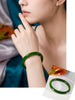 A woman wearing a natural Canadian Polar Jade bangle (AA+ Grade) in a vibrant spinach green color, showcasing its smooth texture. The bottom right features a close-up inset of the same jade bracelet resting on a white card to highlight its translucent, fine mineral quality. 一位女士佩戴着天然加拿大北极玉（AA+级）圆条手镯，展现出细腻温润的质感与高贵的菠菜绿（鲜绿）色泽。右下方附带一张该玉镯置于白纸之上的特写效果图，突显其均匀、通透的玉质。