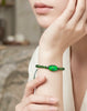 A person wearing a handcrafted beaded bracelet made of green Canadian Polar Jade and an iridescent genuine Ammolite doublet gemstone on her wrist.
